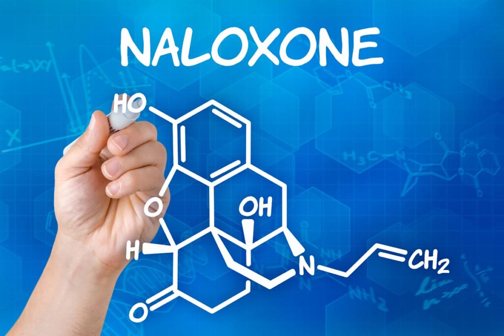 Hand with pen drawing the chemical formula of naloxone